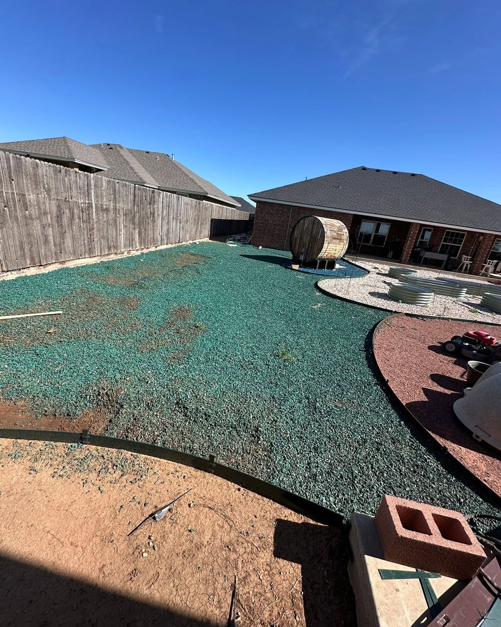 Backyard sprayed with fresh hydroseed beside new rock beds and edging